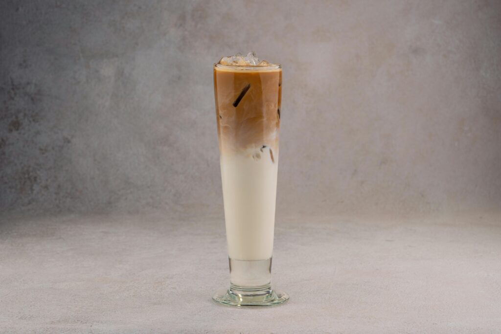 A refreshing iced coffee latte in a tall glass on a neutral gray background.
