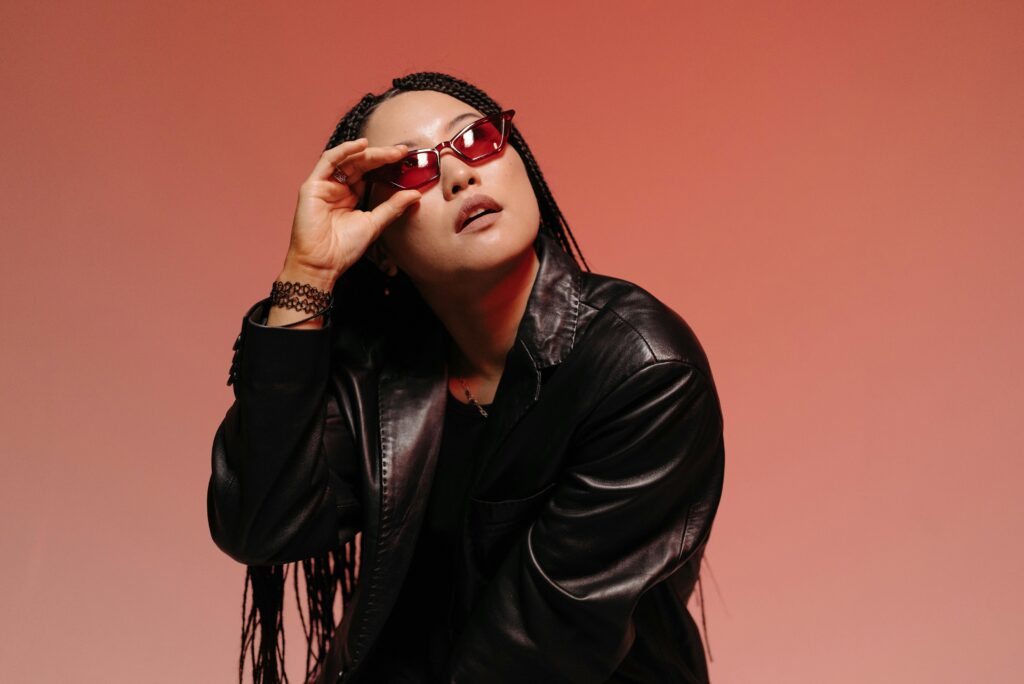 Fashionable portrait of a woman posing confidently in a studio with a red background.