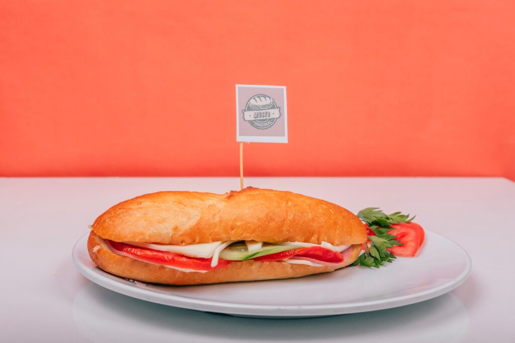 Fresh sub sandwich filled with veggies on a white plate against an orange background.