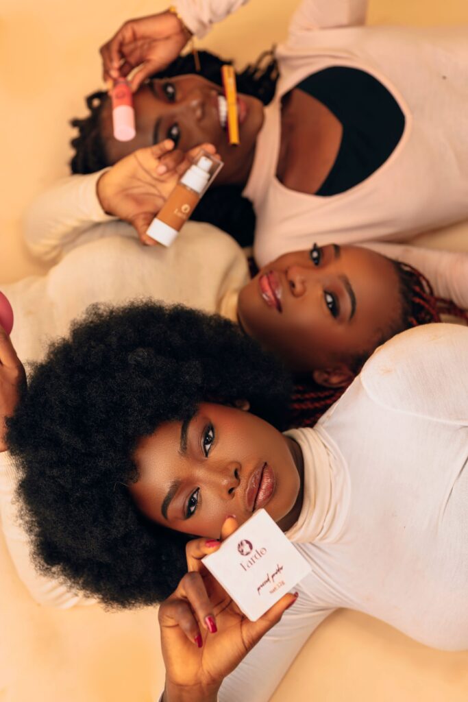 Three women lying down, showcasing various beauty products in a portrait setting.