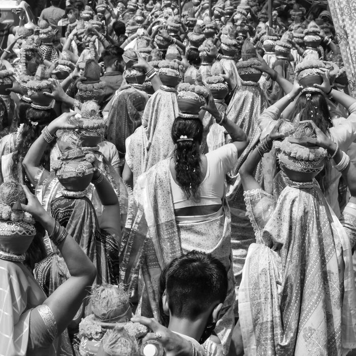 Monochrome image of women in traditional attire participating in a cultural festival procession.