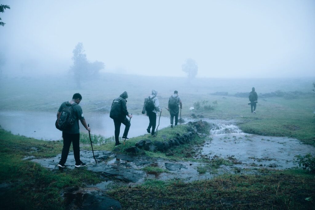 A group of hikers trekking through foggy countryside, creating a sense of adventure in misty weather.